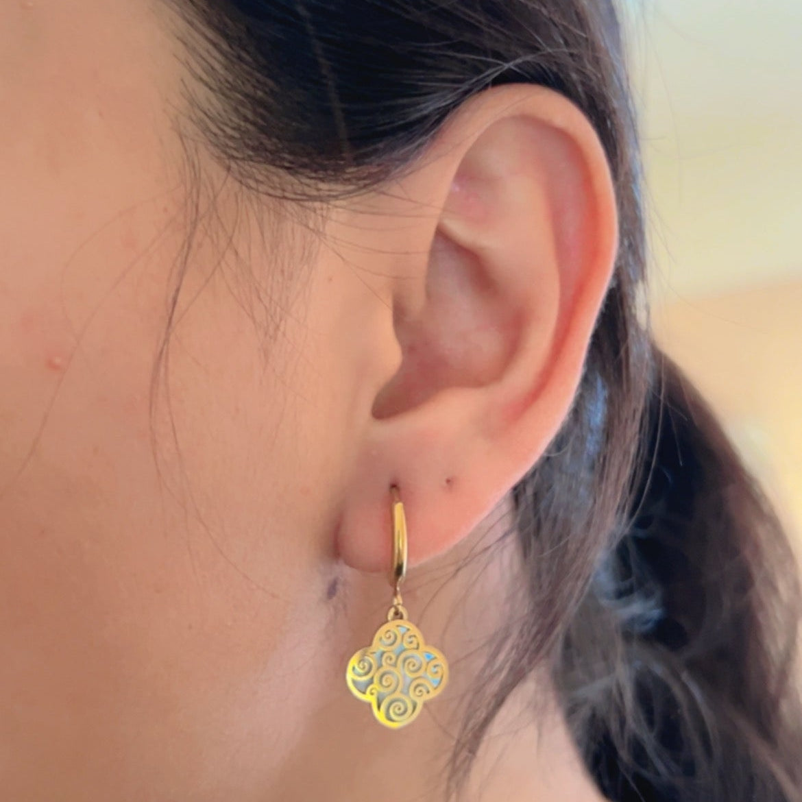 gold drop earrings with engraved pattern design on light background