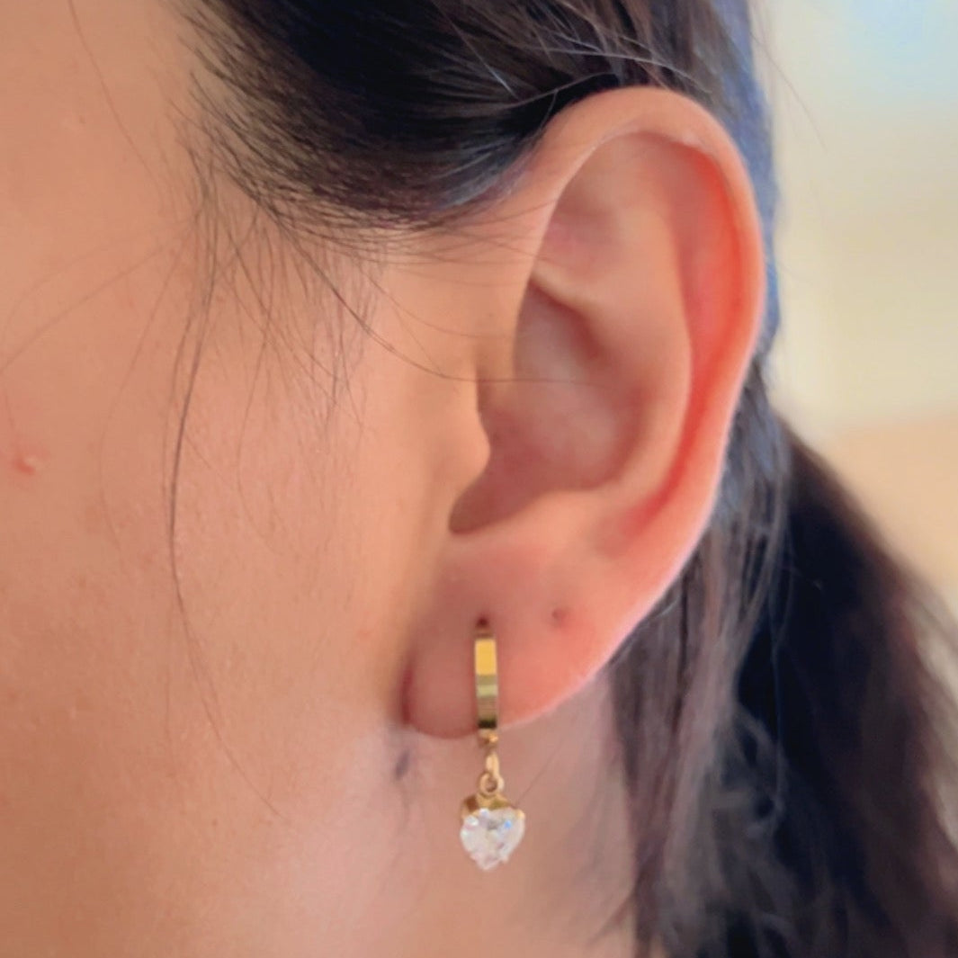 gold mini hoop earrings with crystal drop on light background