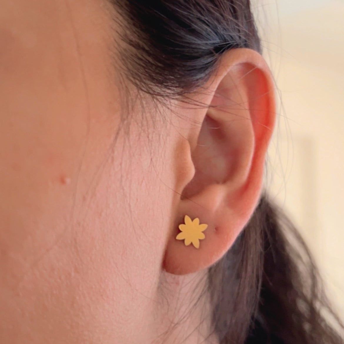 gold flower stud earrings on light background