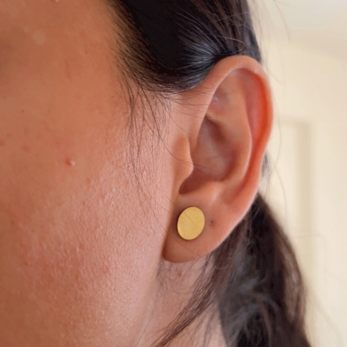 matte oval gold stud earrings on soft neutral background