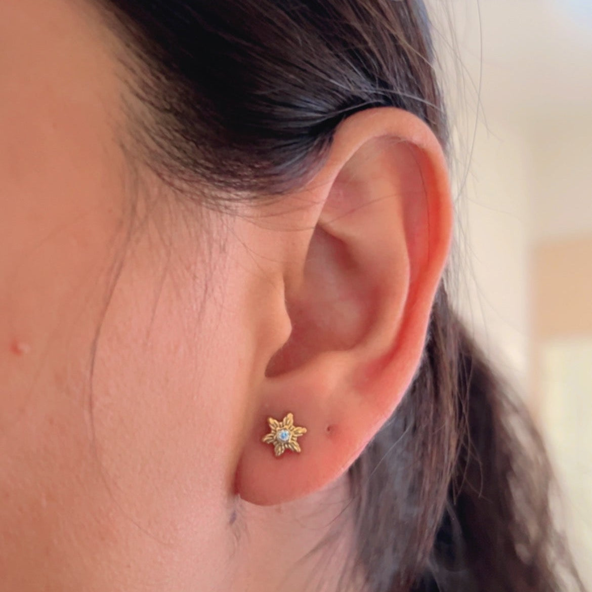 gold star shaped stud earrings with crystal center on neutral background