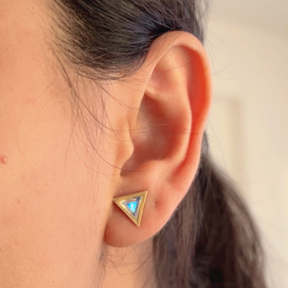 triangle gold stud earrings with crystal center on neutral background