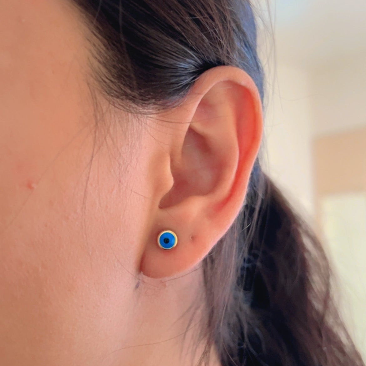 blue evil eye stud earrings with gold border on soft background