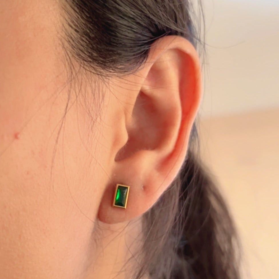 green rectangular stud earrings with gold frame on soft background