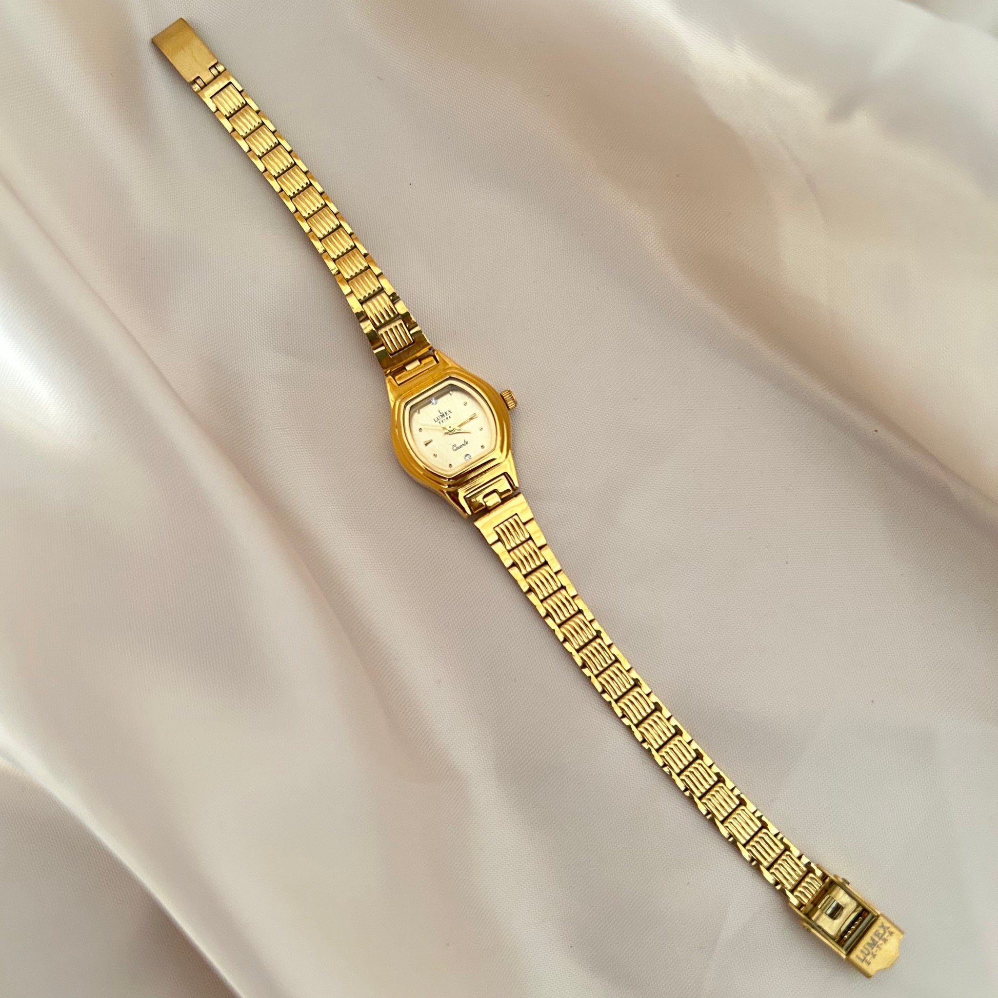 Gold Circle dial wristwatch with linked bracelet placed on soft beige satin background, elegant minimal design.