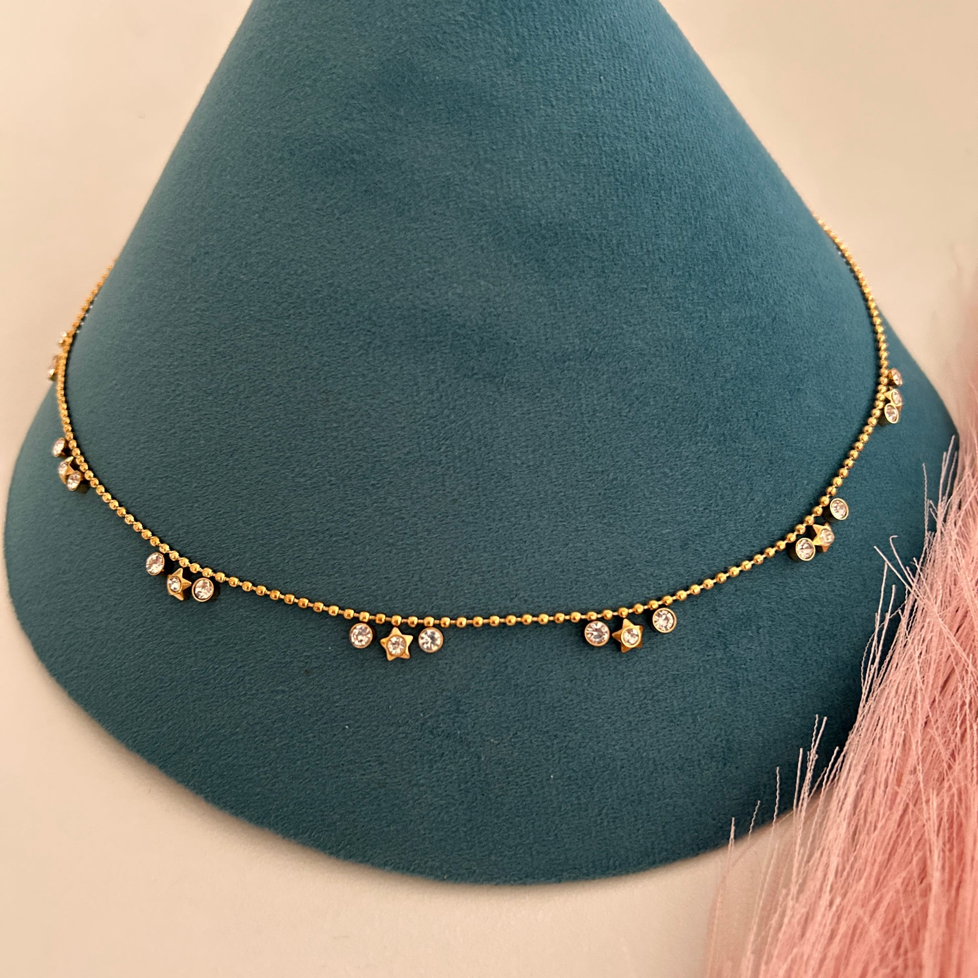 Close-up gold waist band with circular crystal drop pendants evenly spaced.