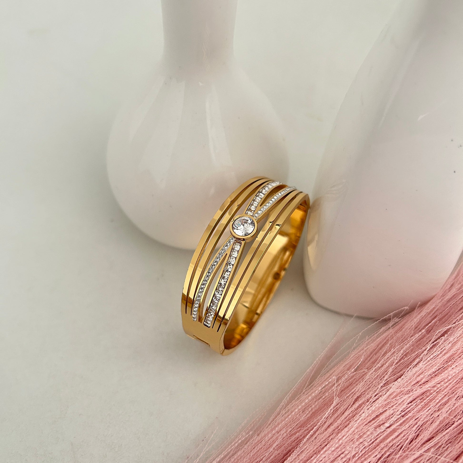 Gold bangle bracelet with round crystal centerpiece.