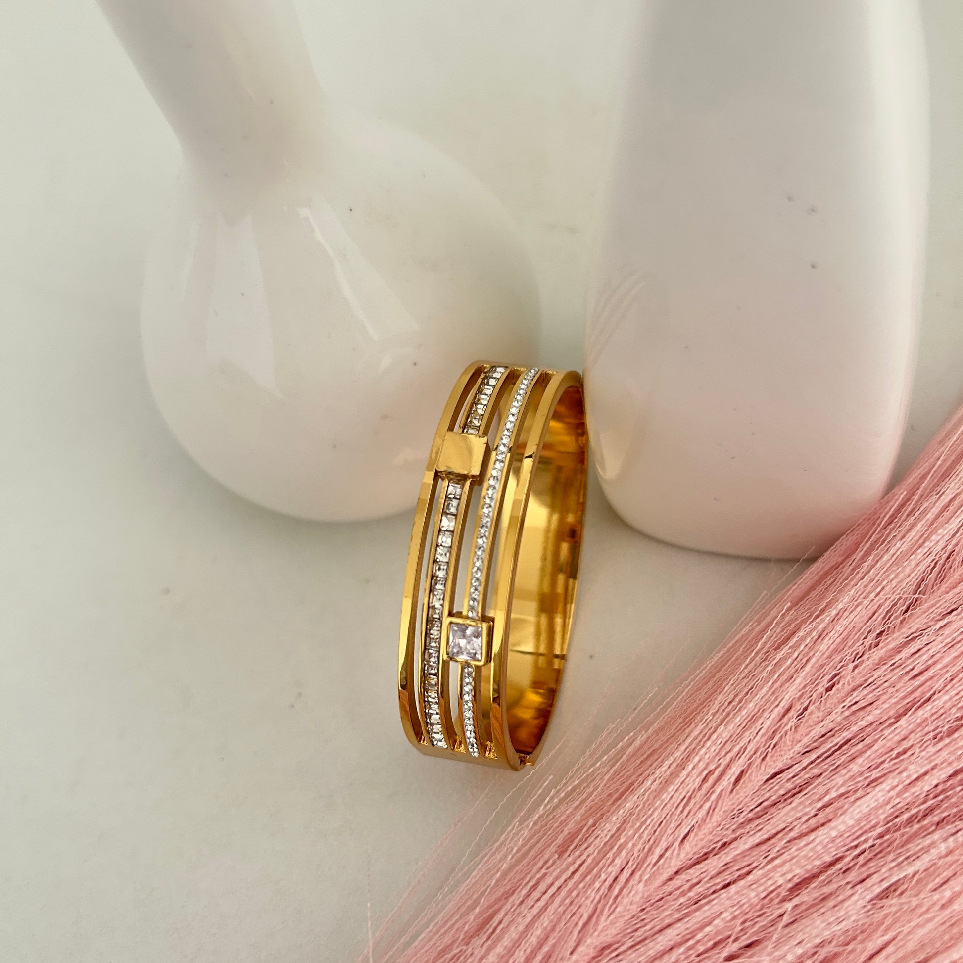 Gold layered bangle with crystal bars and square stone.