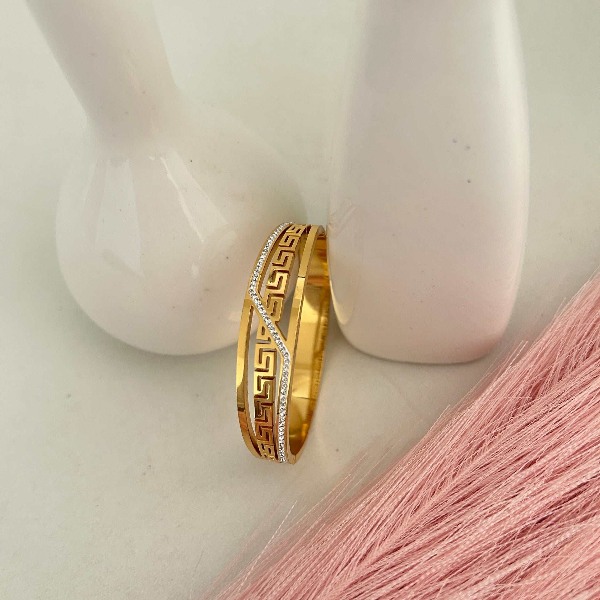Gold bangle with Greek key design and crystal accents.