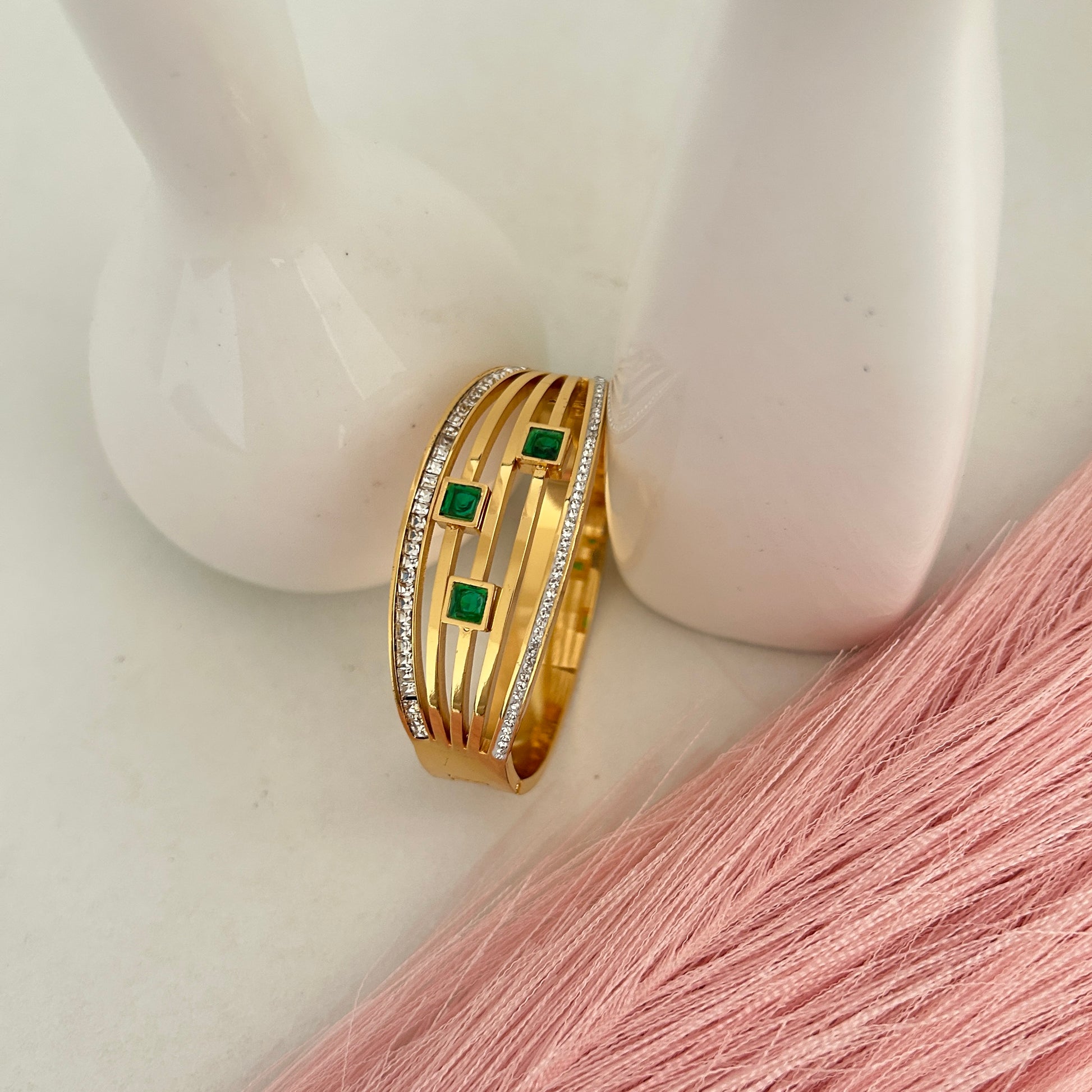 Gold bangle bracelet with green square stones and crystal edges.