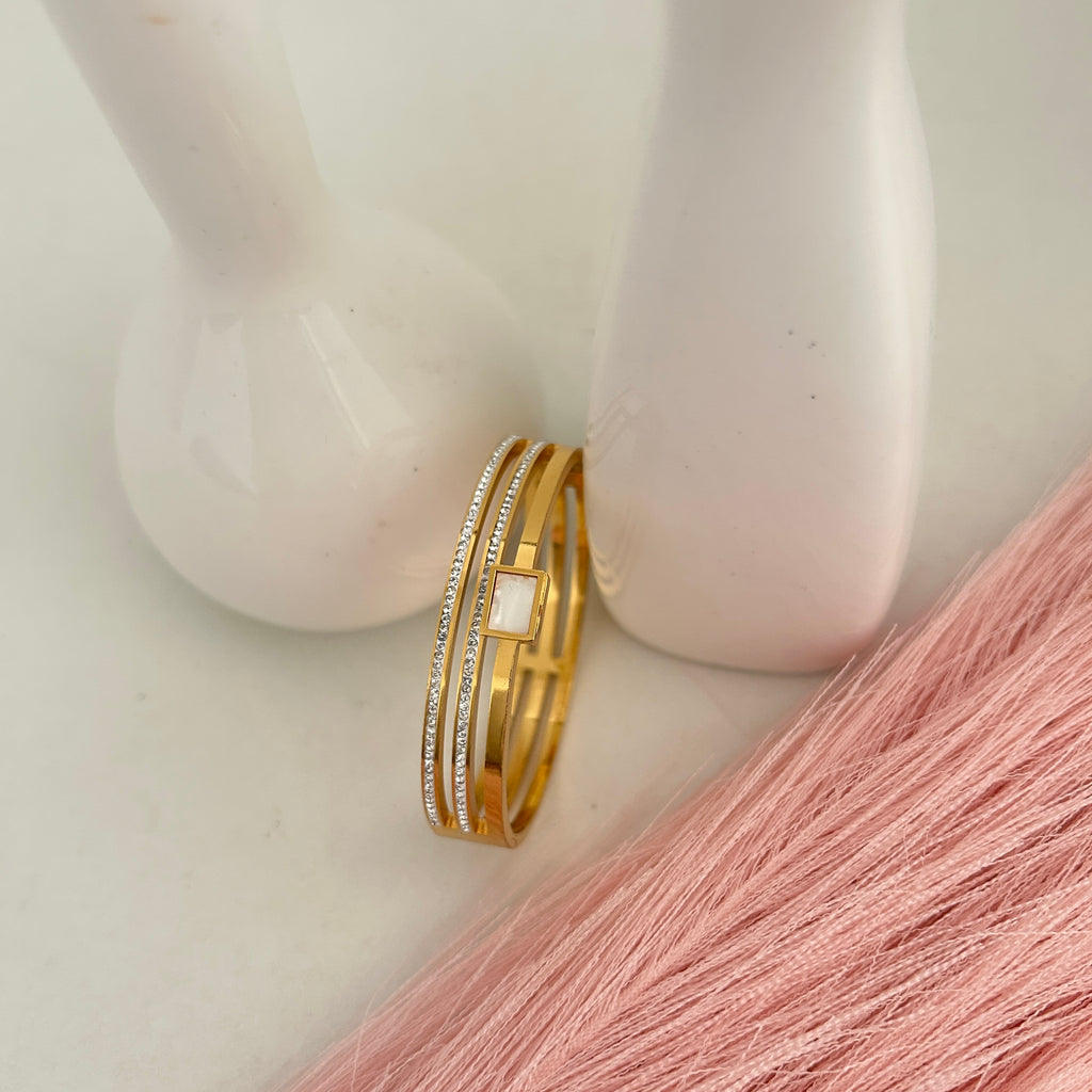 Gold layered bangle with square centerpiece stone.