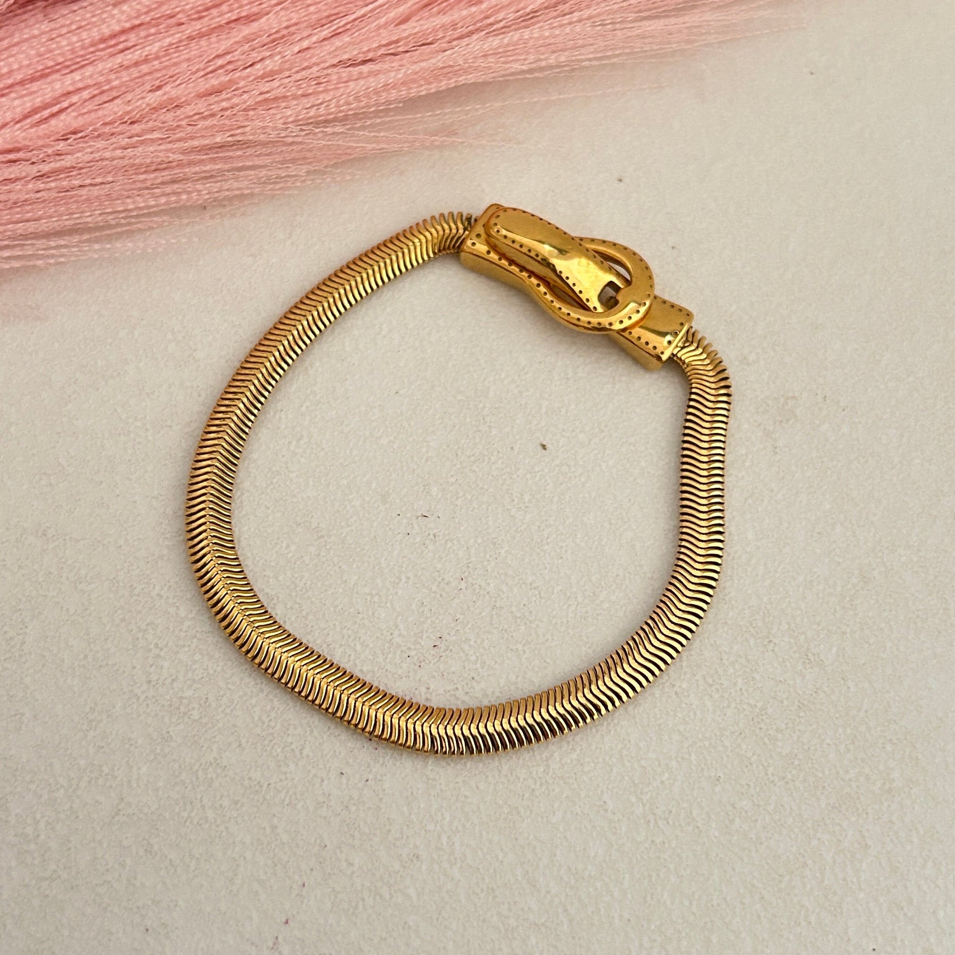 Smooth gold snake chain bracelet with clasp closure.