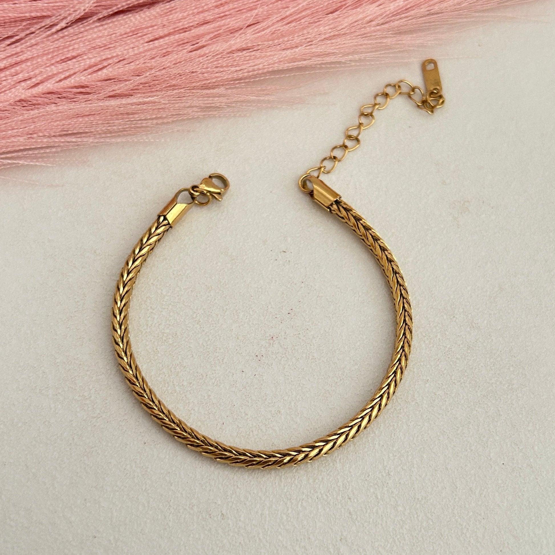 Gold braided rope bracelet with adjustable chain closure.