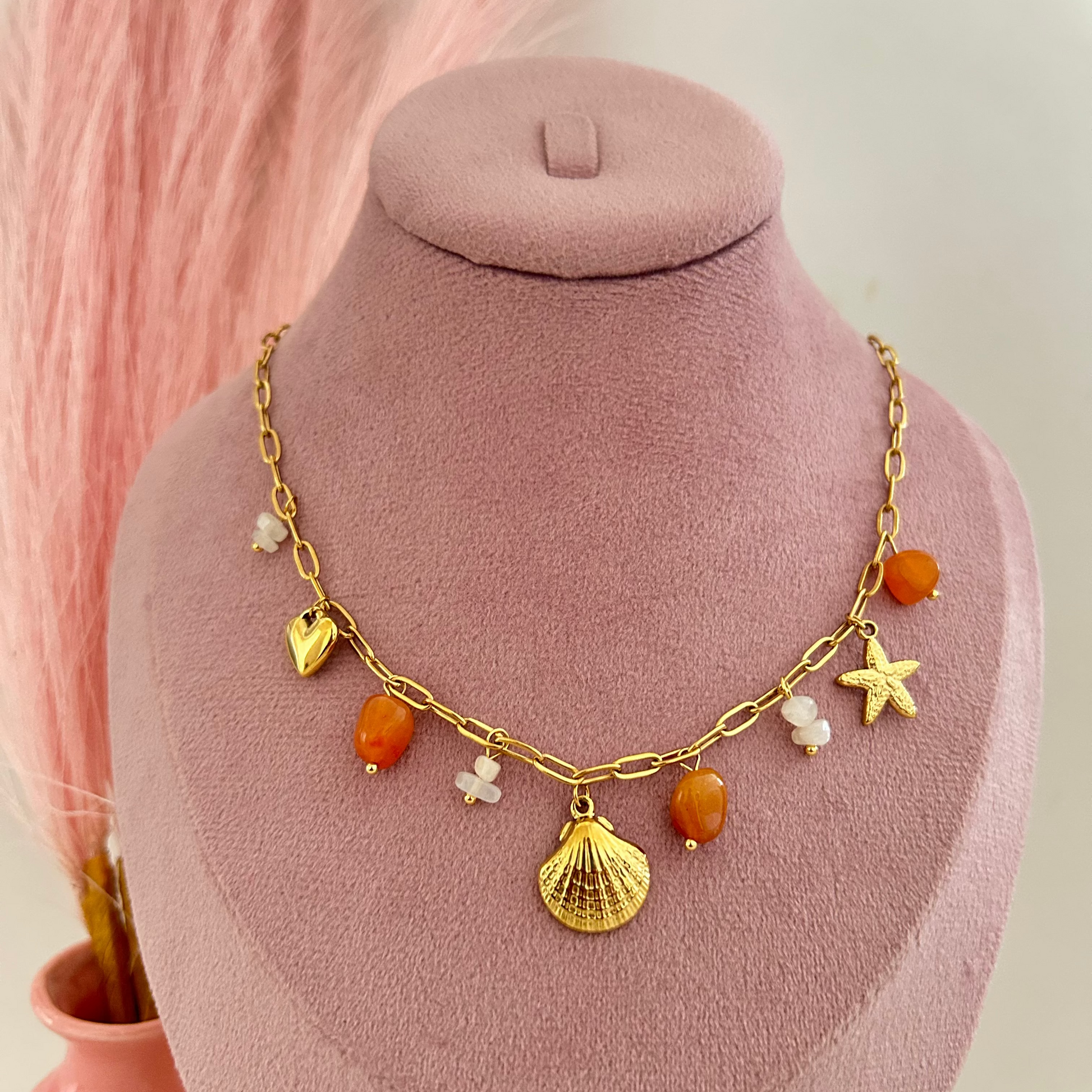 Gold chain necklace with shell charm and orange gemstone beads.
