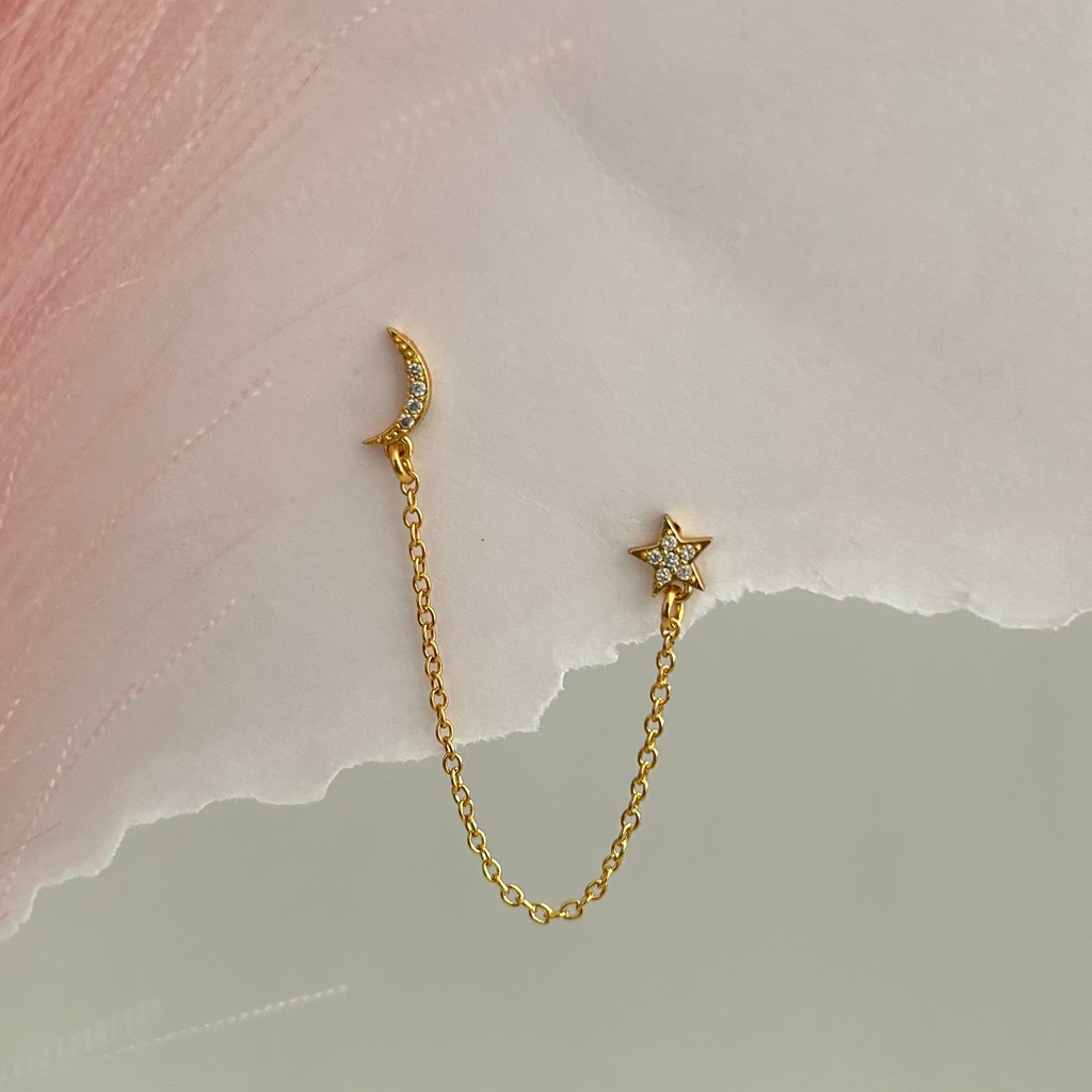 Gold dual piercing earring with moon and star charm connected by chain