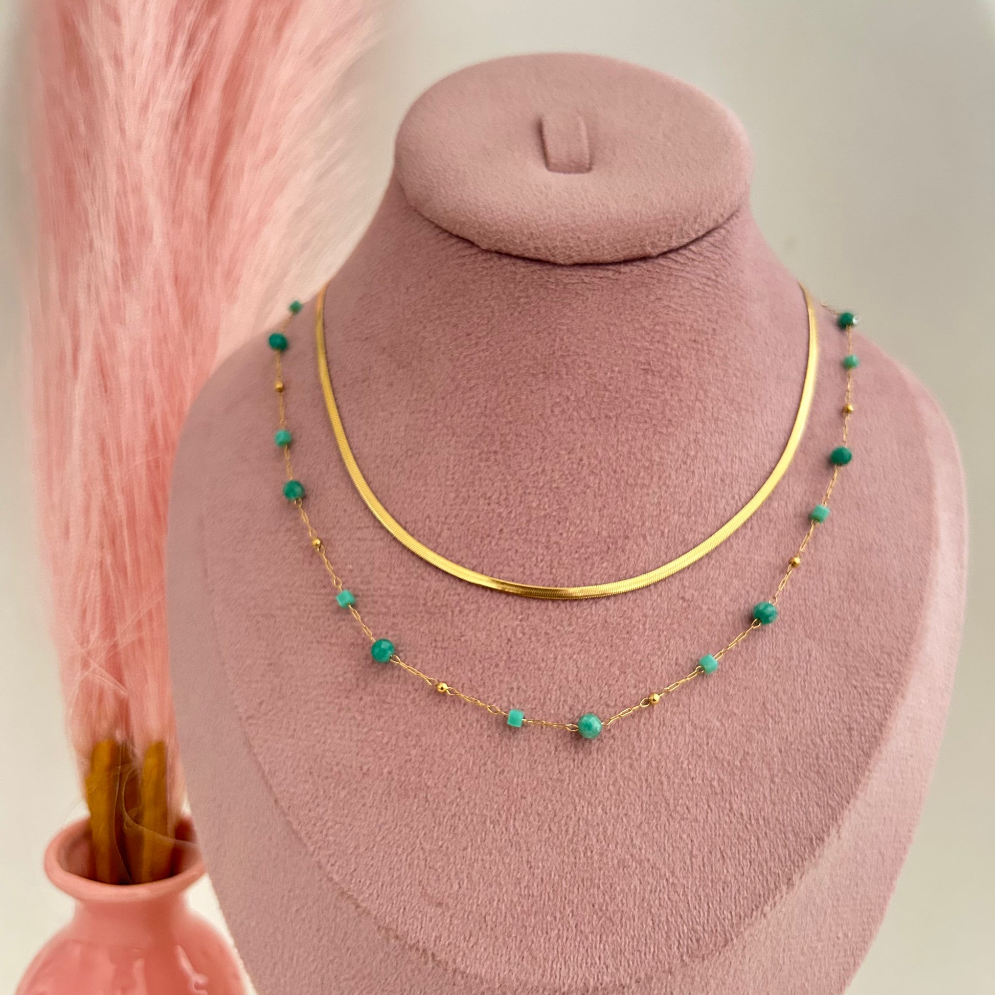 Gold layered necklace with turquoise beads and flat chain design on display bust