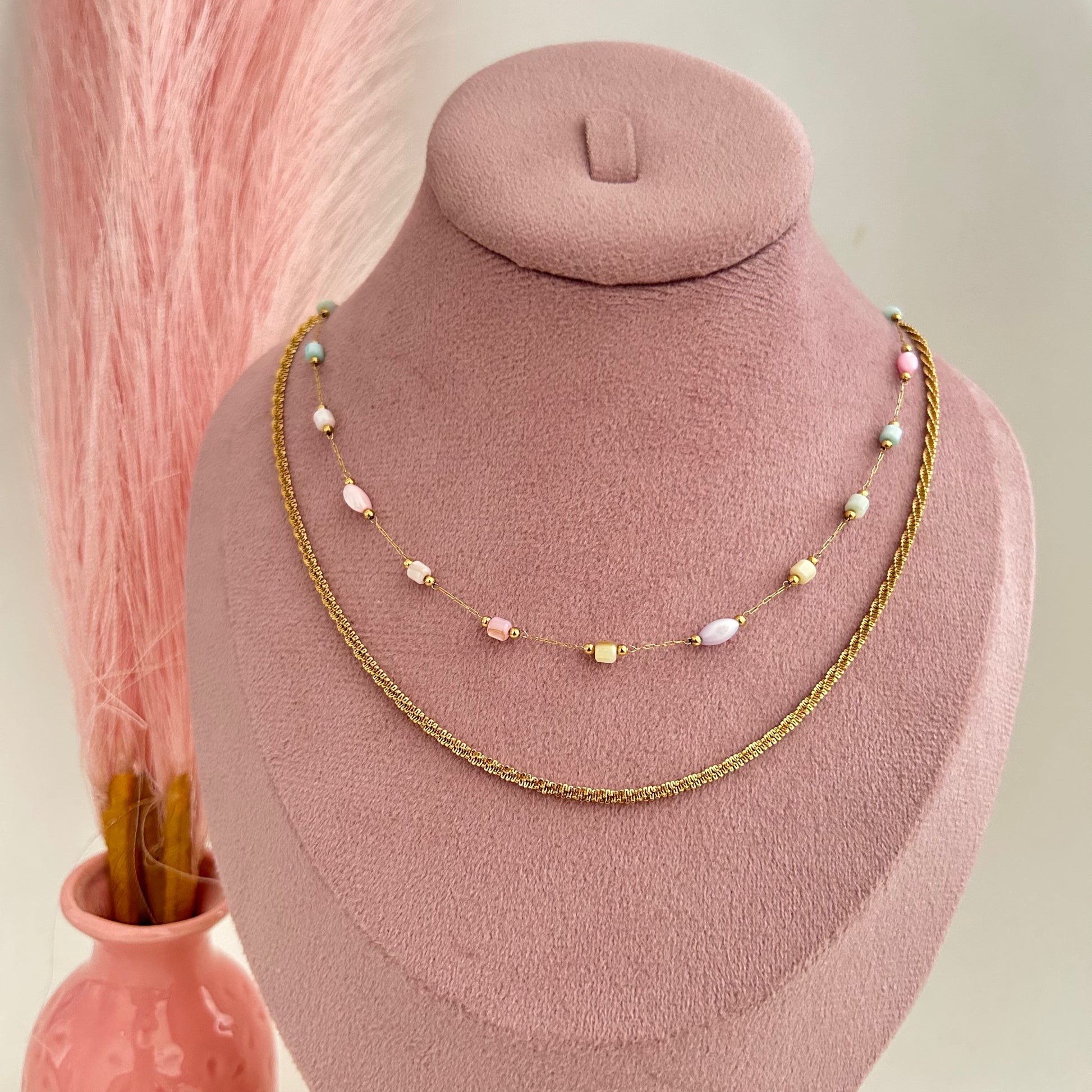 Gold layered necklace with white pearl beads on pink display