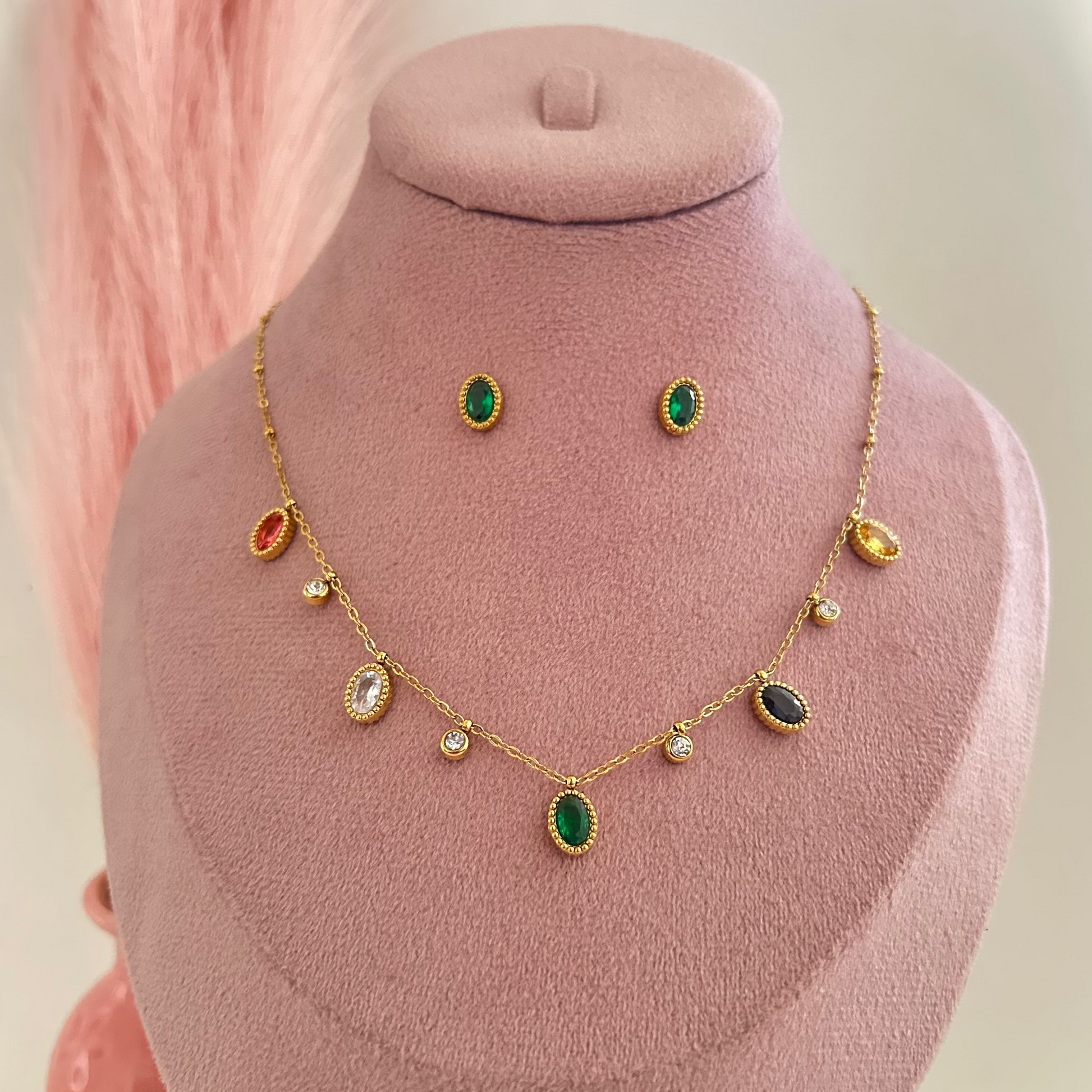 Close-up gold necklace with multicolor teardrop charms and green pendant with matching earrings