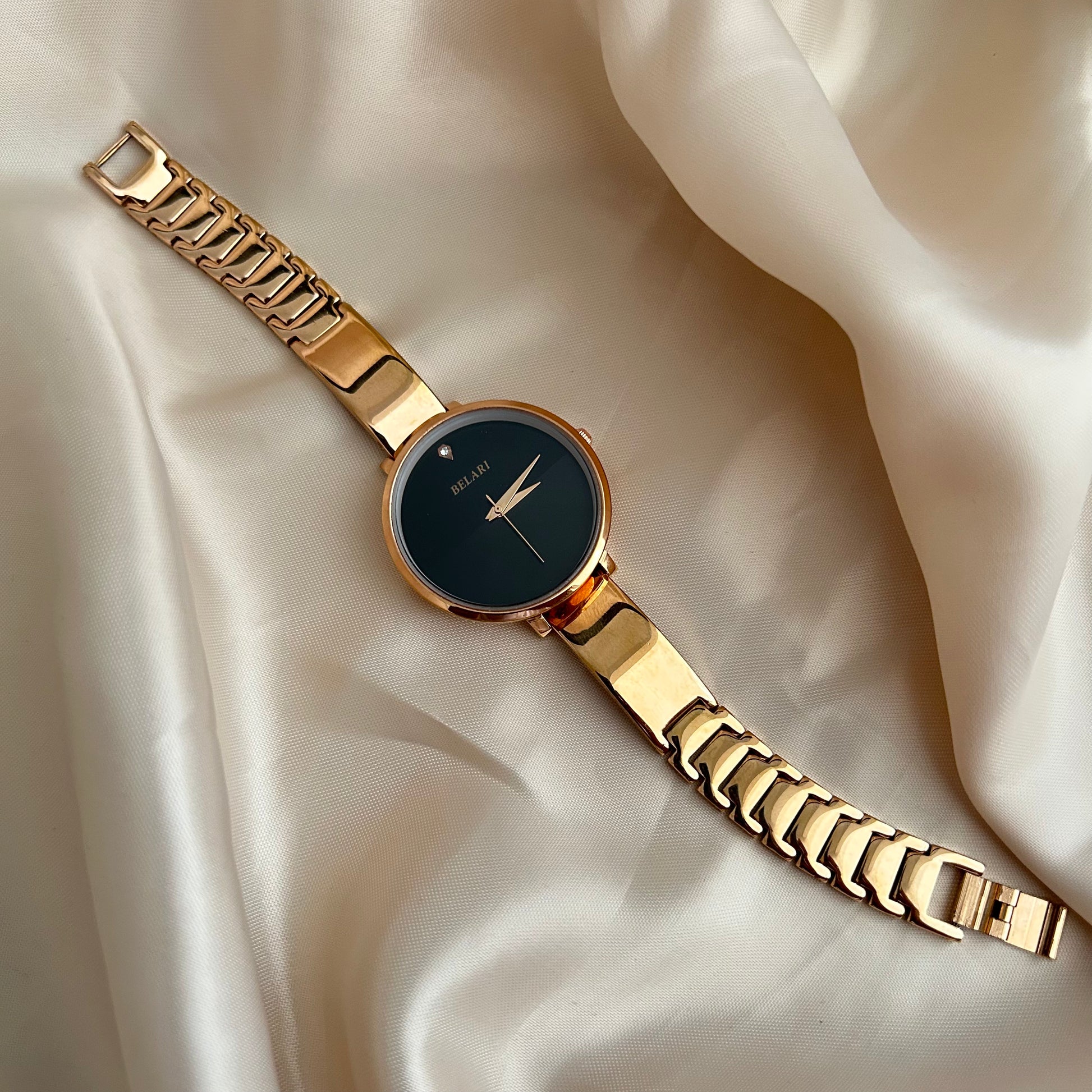 Rose gold wristwatch with round dial placed on satin fabric background.