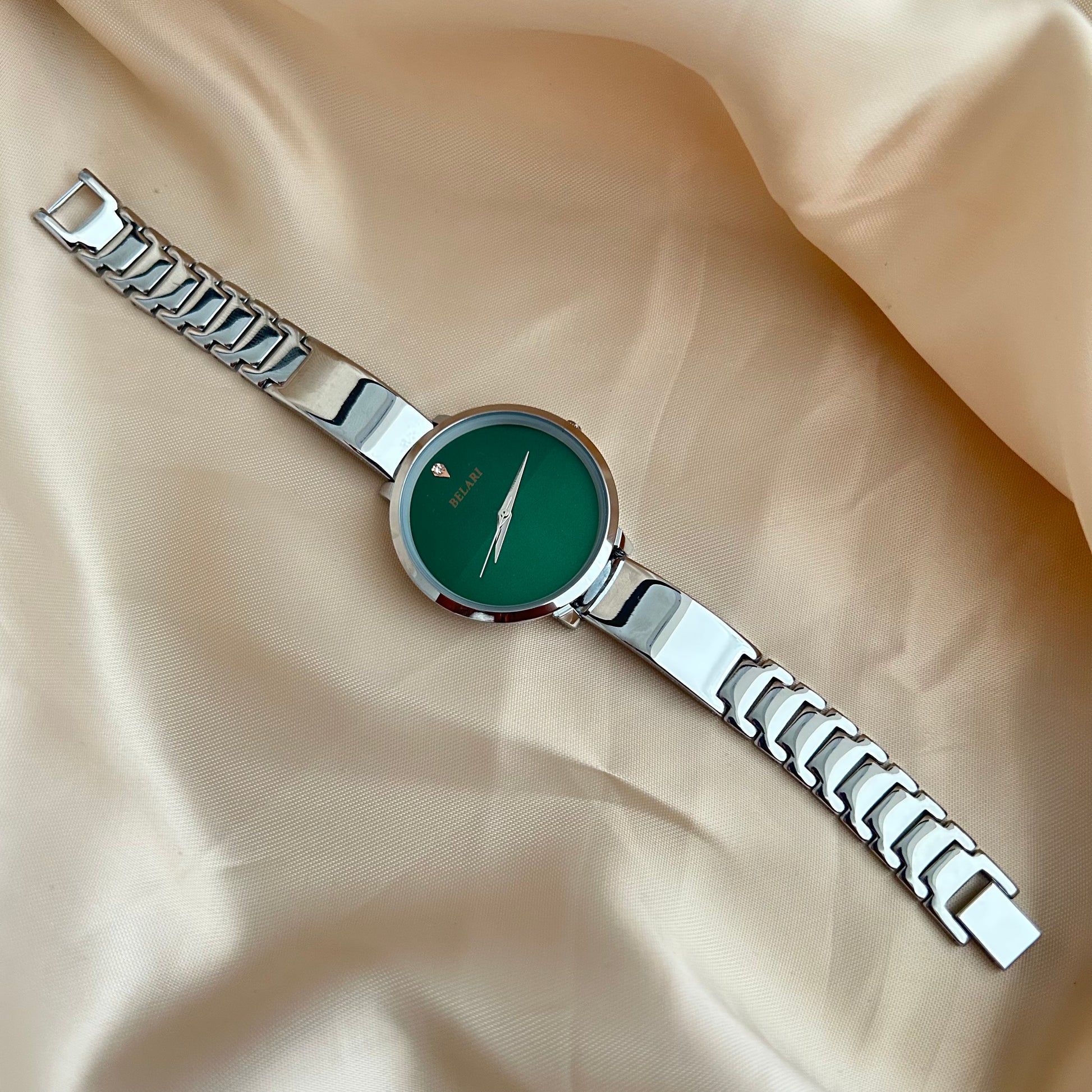 Silver Body wristwatch with silver strap on soft fabric background.