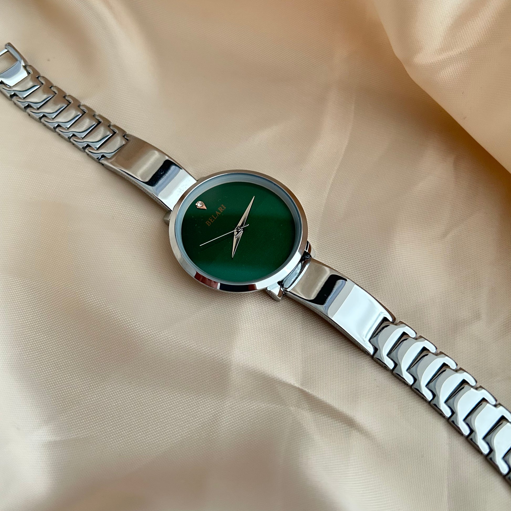 Silver Body wristwatch with silver strap on soft fabric background.