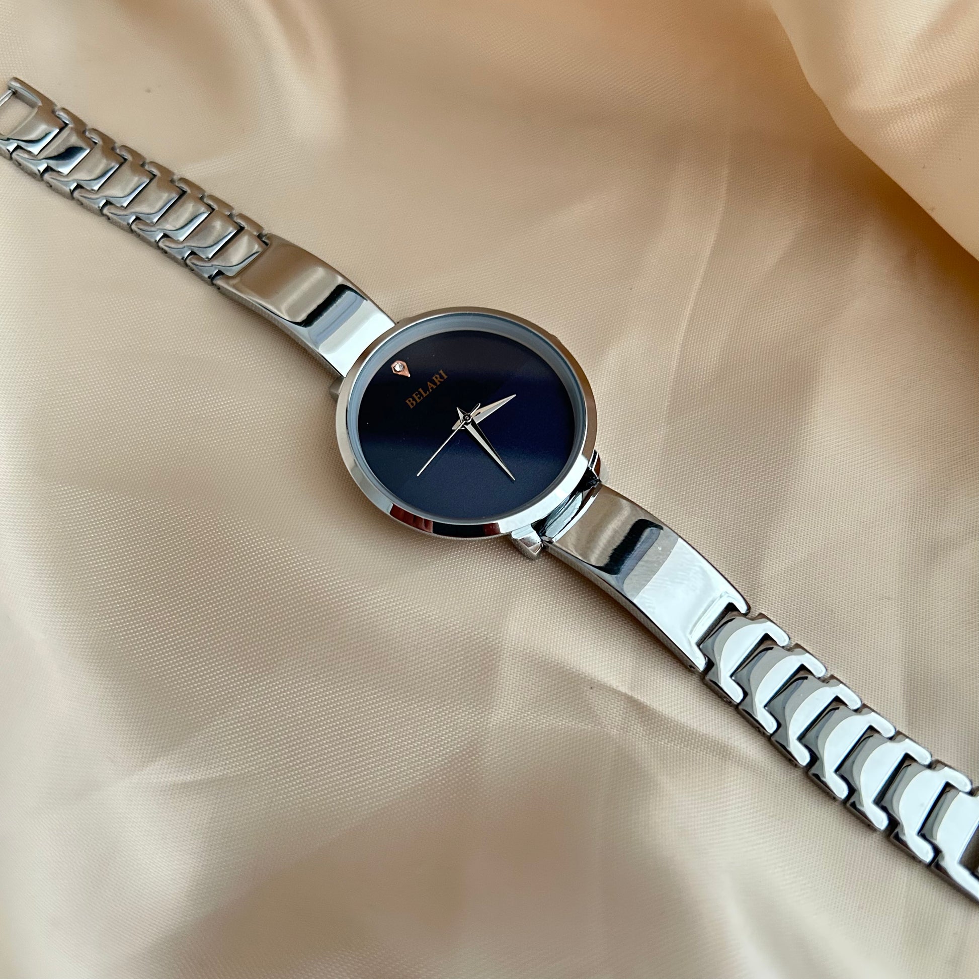 Silver Body wristwatch with silver strap on soft fabric background.