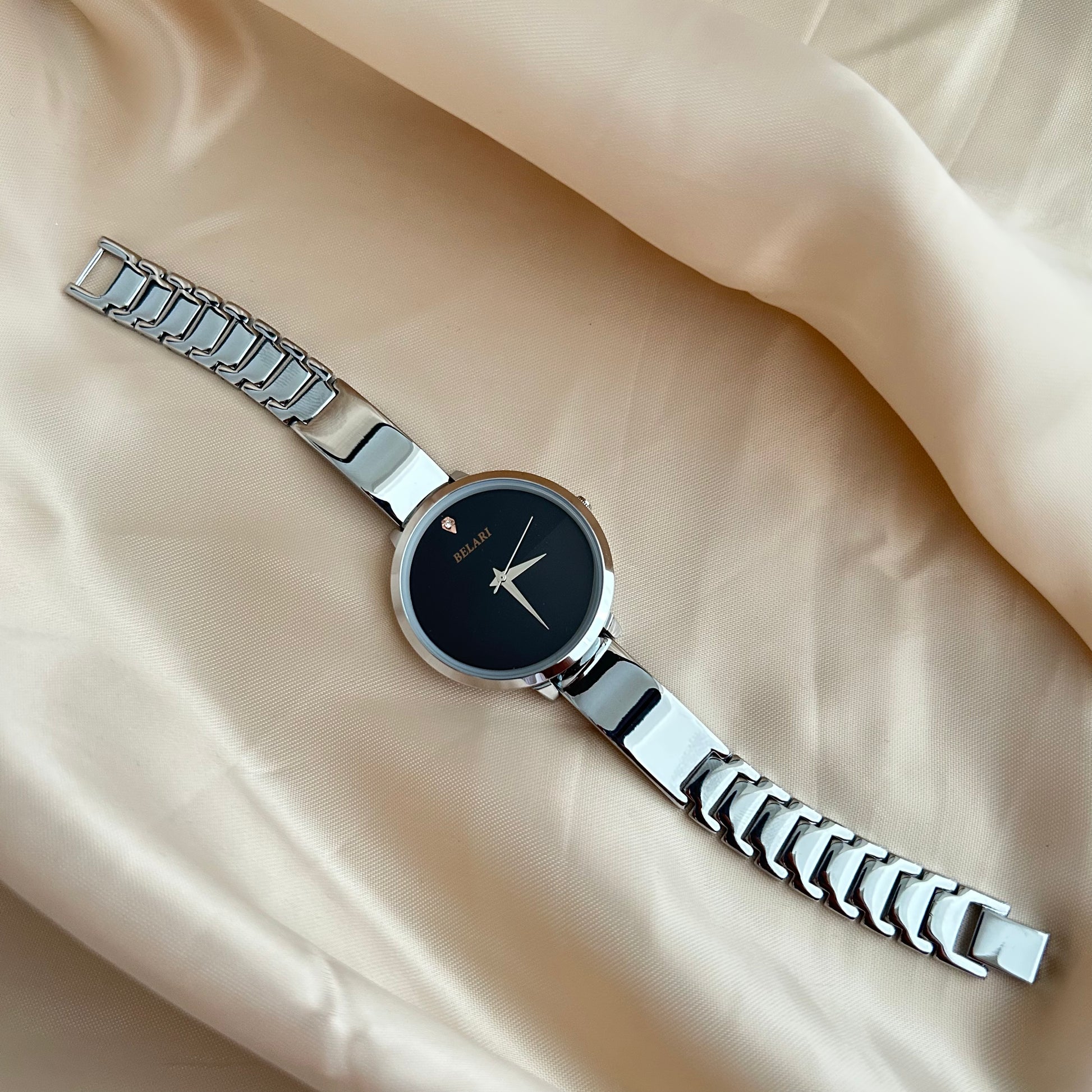 Silver Body wristwatch with silver strap on soft fabric background.