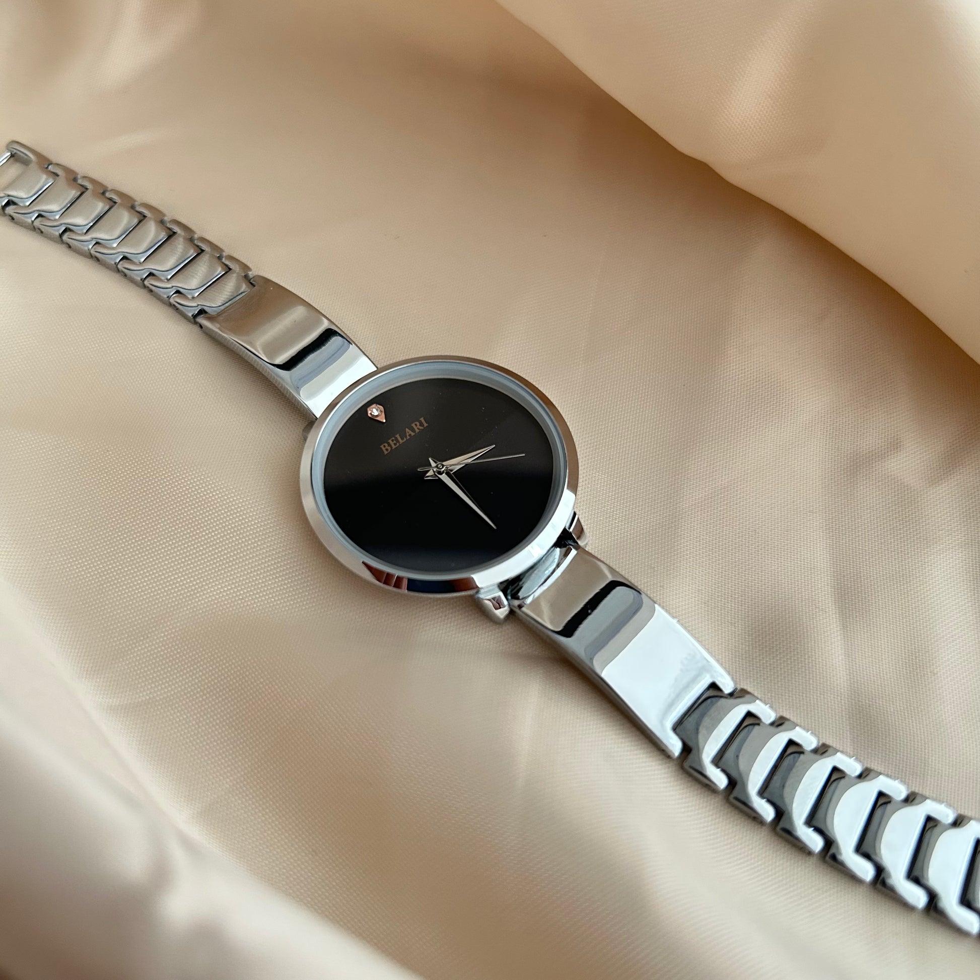 Silver Body wristwatch with silver strap on soft fabric background.