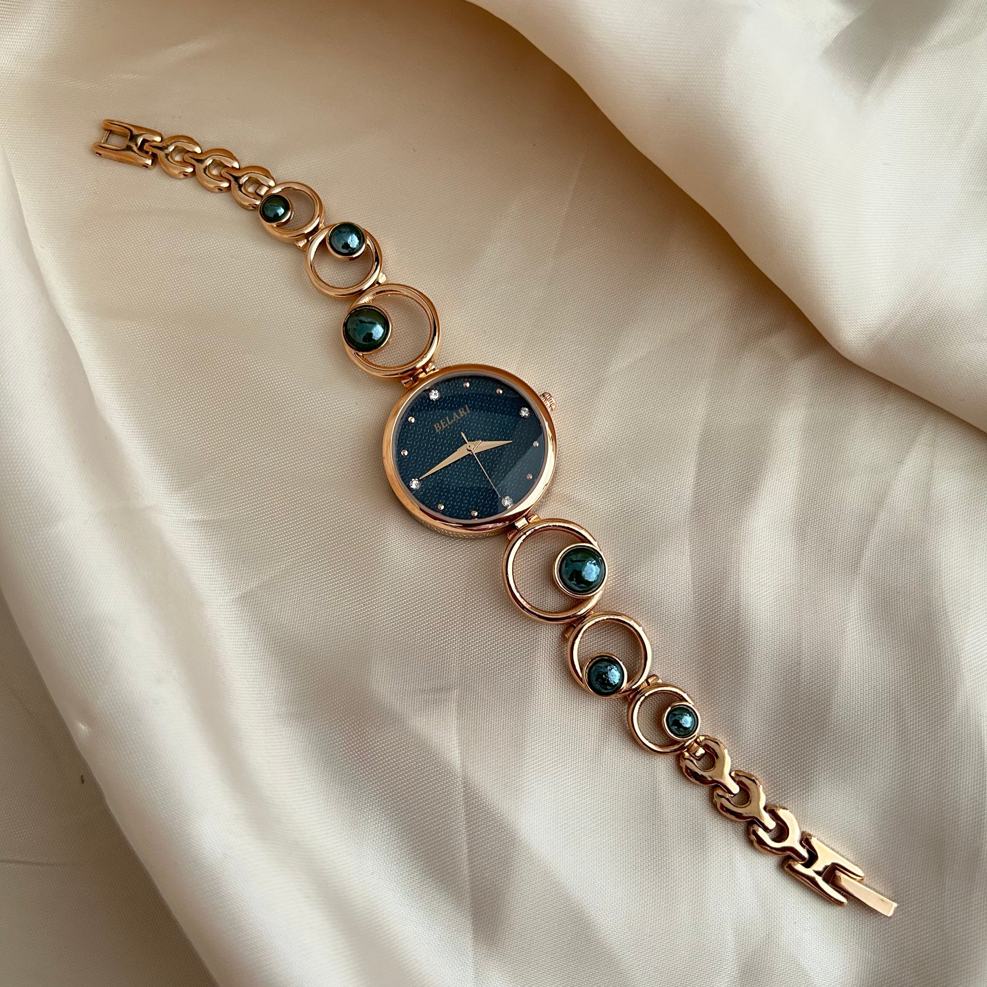 Rose gold wristwatch with pearl bracelet design and round dial on soft satin background.