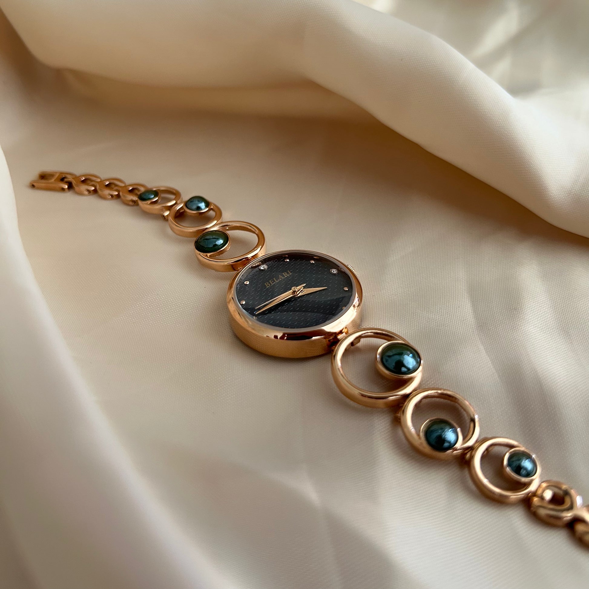 Rose gold wristwatch with pearl bracelet design and round dial on soft satin background.