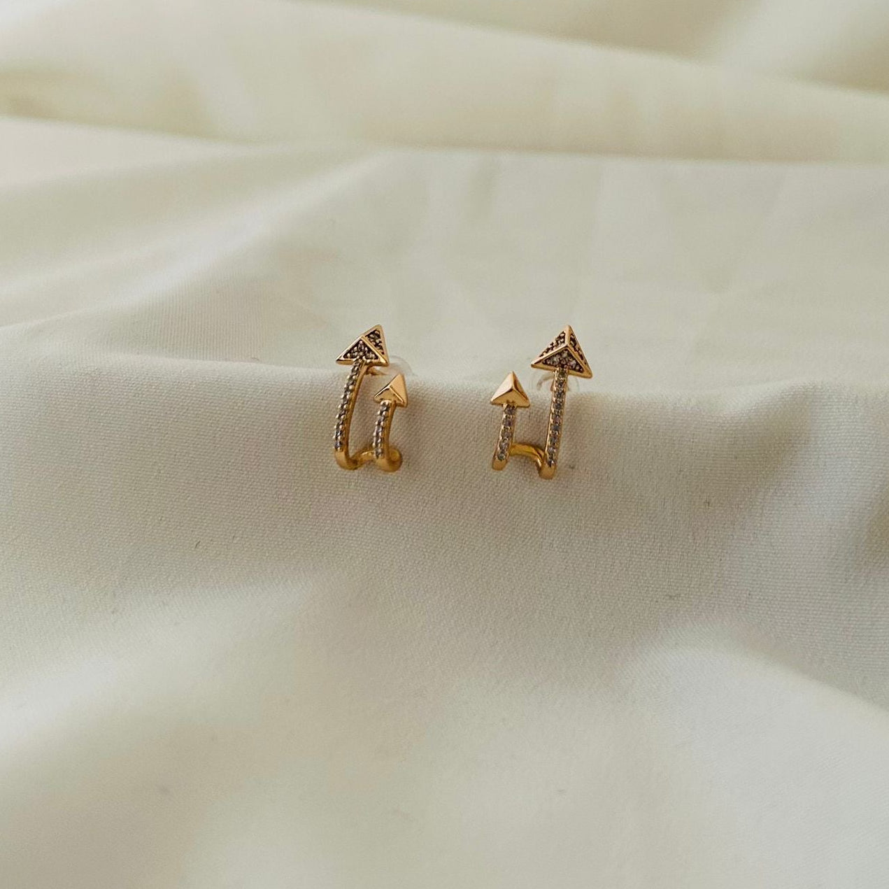 Stylish arrow-shaped gold earrings with crystals.