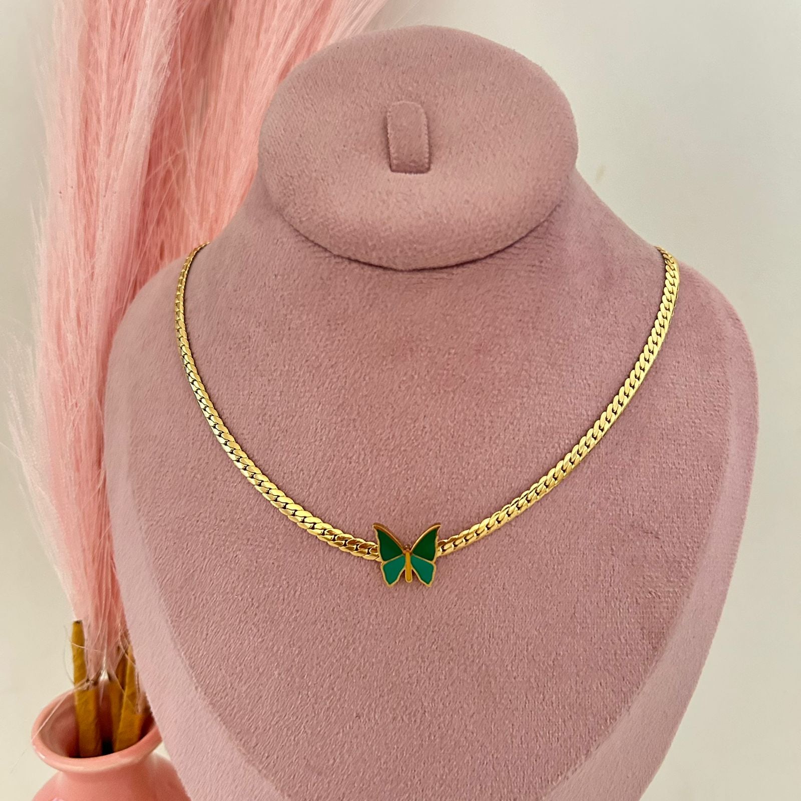 Gold chain necklace with green butterfly pendant displayed on mannequin bust, elegant feminine jewelry