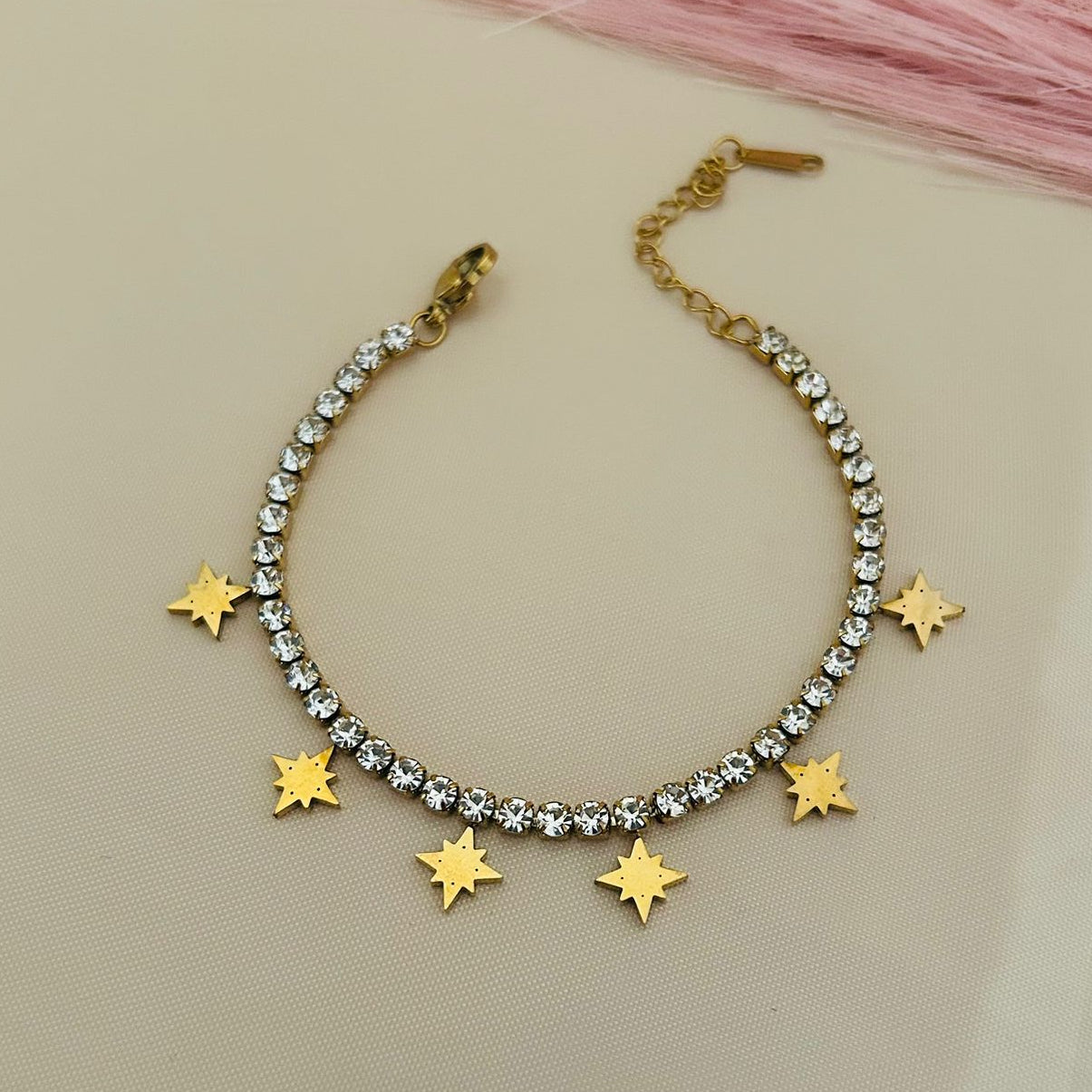 Diamond bracelet with gold star charms hanging, stylish celestial jewelry design on beige background